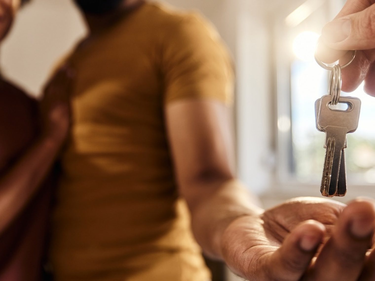 Close up of real estate agent giving house keys to couple.